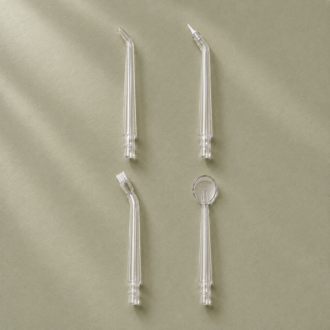 Les quatre embouts AquaPulse One : standard, parodontal, orthodontique et gratte-langue, présentés sur fond sauge.