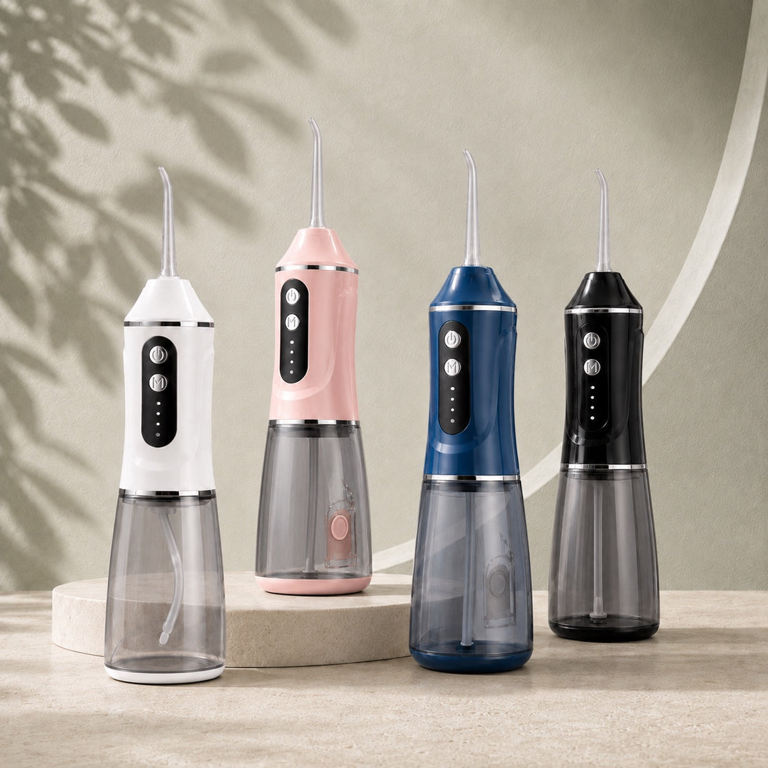 Les quatre coloris AquaPulse One réunis : Blanc Nacré, Rose Poudré, Bleu Horizon et Noir Minuit, sur un décor de pierre claire et sauge.